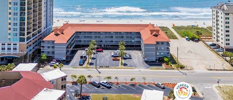 A hotel with a parking lot and a view of the ocean.