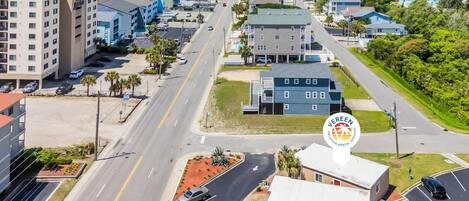 A coastal town with a mix of residential and commercial buildings, a main road, and a beach in the background.