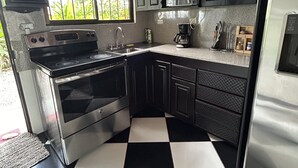 Uma cozinha com piso xadrez em preto e branco, eletrodomésticos de aço inoxidável e armários de madeira escura.