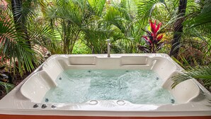 Uma banheira de hidromassagem rodeada por plantas tropicais exuberantes.