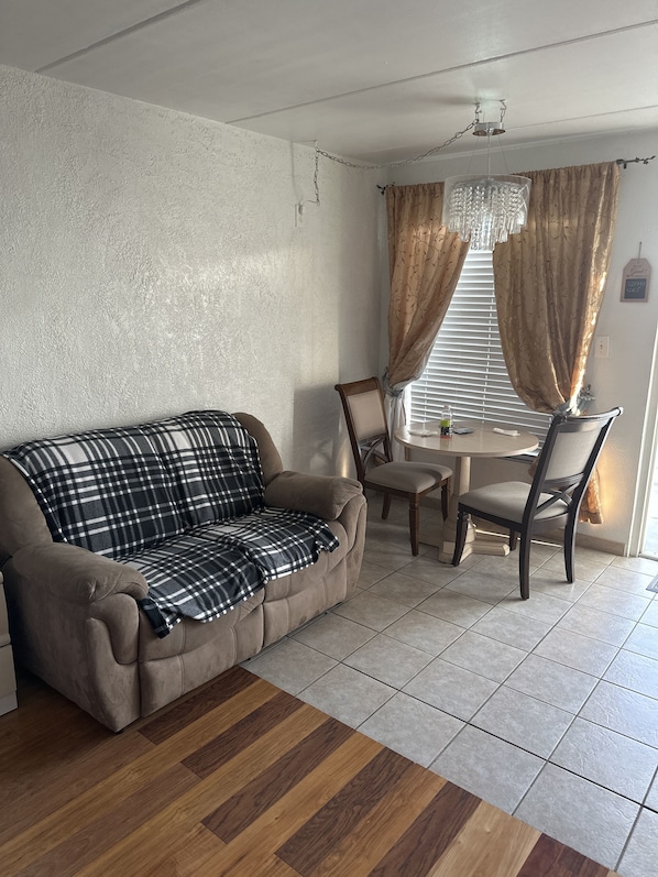 Una sala de estar con un sofá, una mesa de comedor y sillas.