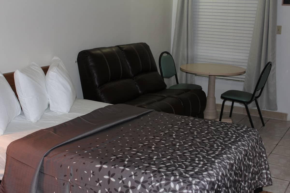 Une chambre d’hôtel avec un lit, un canapé, une petite table et deux chaises.