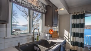 A kitchen with a large window, a sink, and a view of a lake.