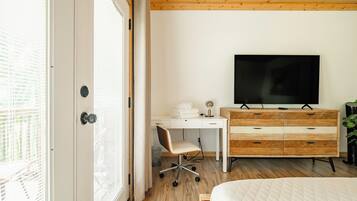 A bedroom with a bed, a desk, a TV, and a dresser.