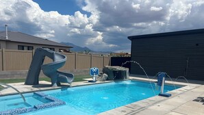 A swimming pool with a slide, a rock feature, and a water fountain. - Red Rock Oasis and Private Pool Getaway! (Moab)