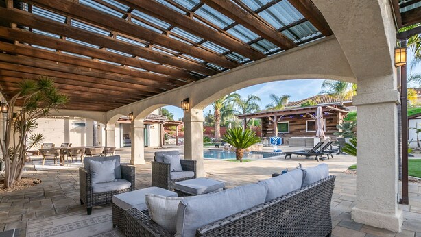 An outdoor patio area with wicker furniture, a pool, and a covered section with a wooden ceiling. - Hidden Gem of SoCal: Game Room, Pool, Spa, & Resort Backyard!  (Vista)