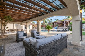 Ein Patio im Freien mit Korbmöbeln, einem Pool und einem überdachten Bereich mit Holzboden.
