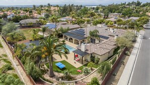 A residential area with houses, a swimming pool, solar panels, and a tennis court. - Hidden Gem of SoCal: Game Room, Pool, Spa, & Resort Backyard!  (Vista)