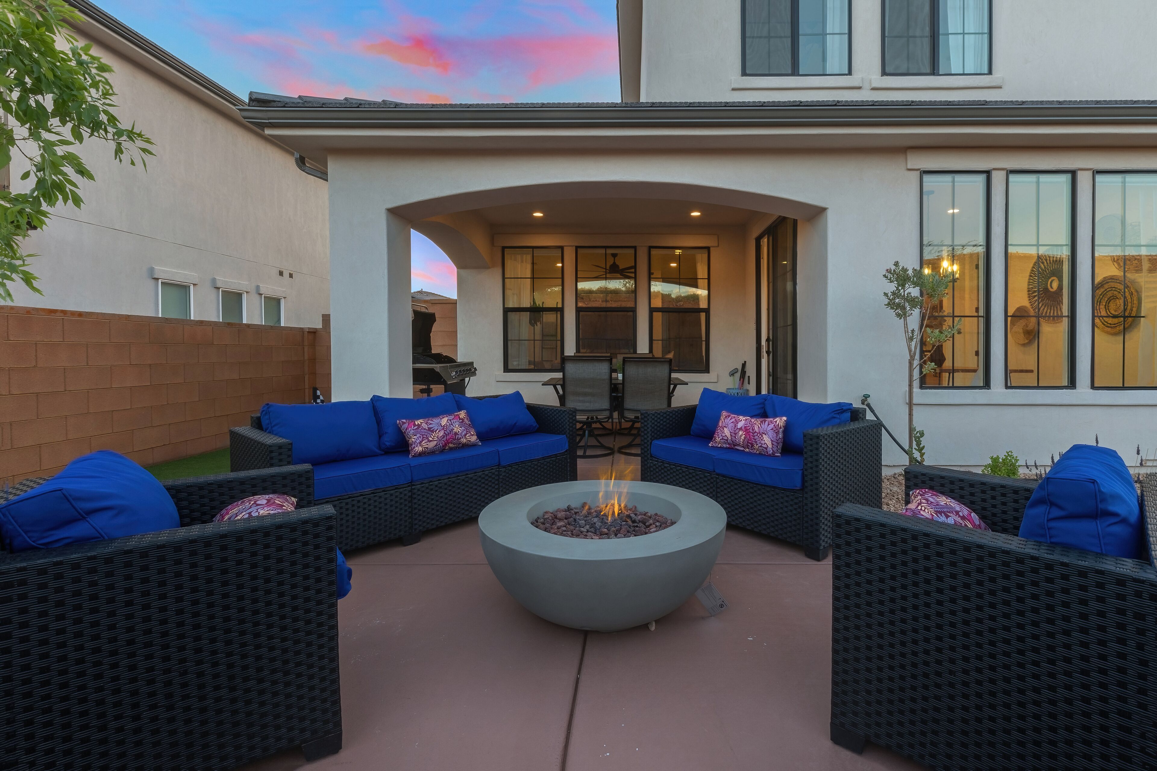 An outdoor patio with wicker furniture and a central fire pit.