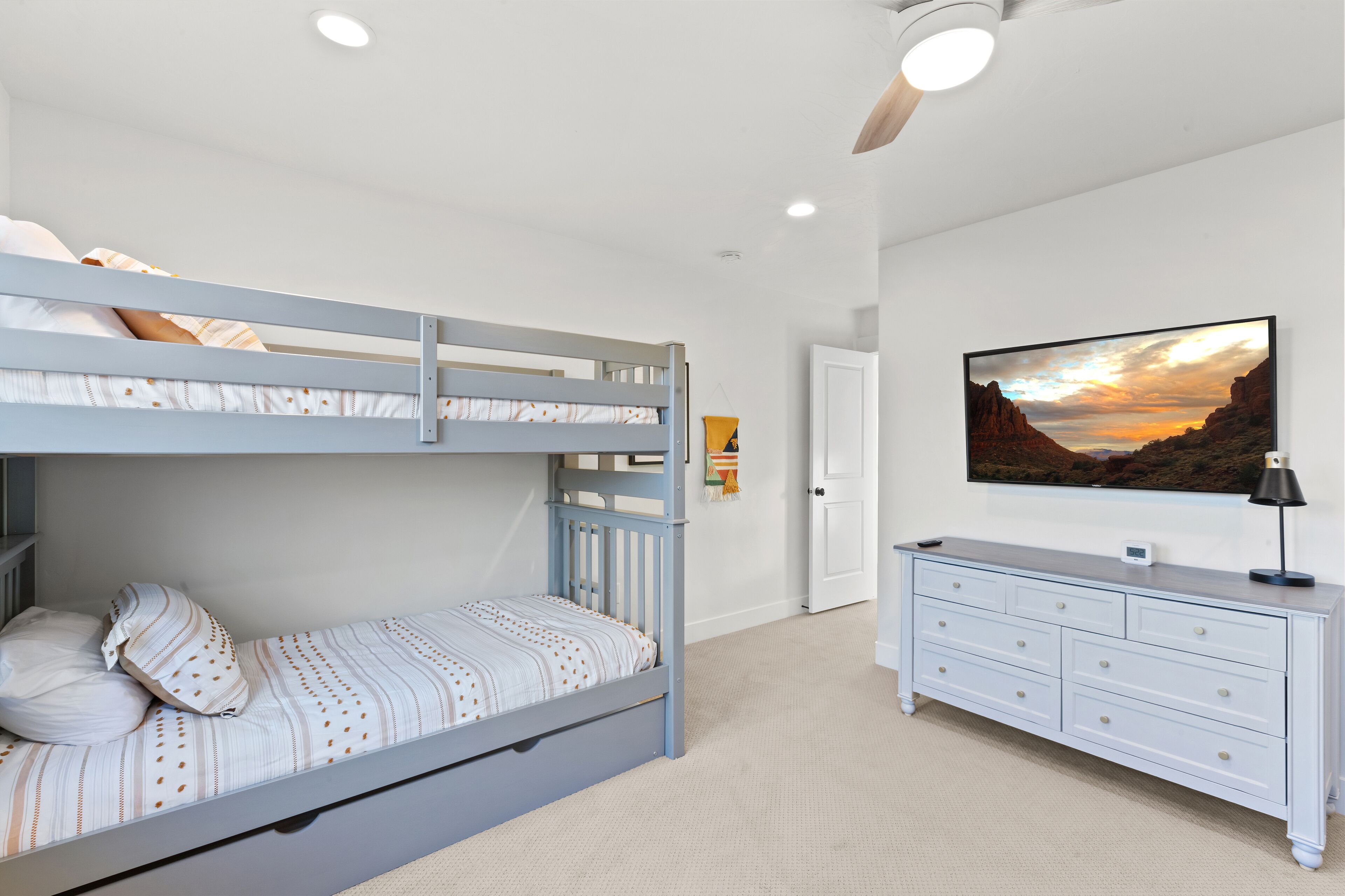 A bunk bed with a lower bunk, a bedside table, and a dresser with drawers.