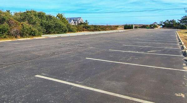 A large, empty parking lot with clearly marked parking spaces and a building in the background. - For-C-Sons - Oceanside 5 BR Home w/Private Pool (Southern Shores)