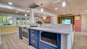 Una cocina moderna con una isla central, electrodomésticos integrados y un amplio ventanal con vistas al exterior.