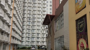A multi-story residential building with balconies, a parking lot, and a building with a mural and signage. - Condo unit at Tagaytay Prime residences (Tagaytay)