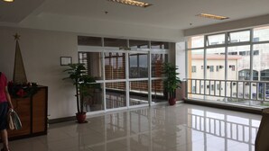 A spacious lobby with a large glass door leading to a balcony, potted plants, and a star decoration on a wooden cabinet. - Condo unit at Tagaytay Prime residences (Tagaytay)