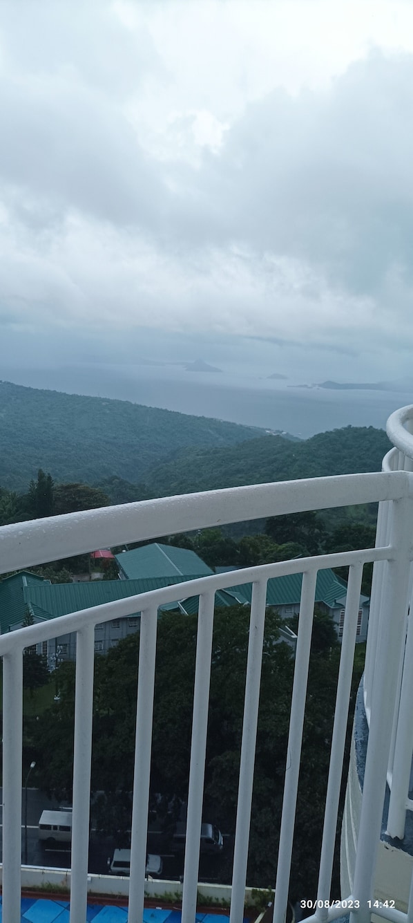 A balcony with a view of a mountainous landscape and a body of water.