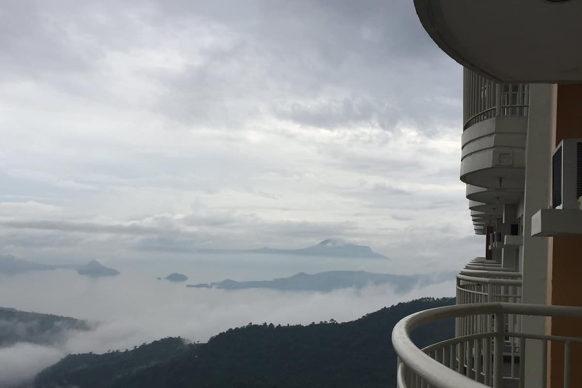 A balcony with a view of a mountainous landscape and clouds.