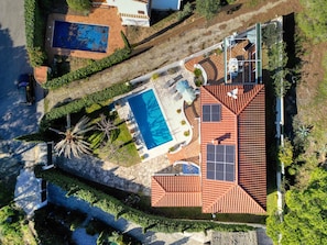 An aerial view of a property with a swimming pool, solar panels, and a patio area.