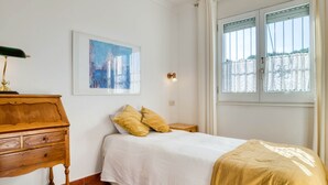A bedroom with a bed, a wooden dresser, a framed painting, and a window with curtains. - AIGUES: Beautiful house with private swimming pool in l'Escala (L'Escala)