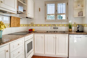 A kitchen with white cabinets, a granite countertop, a stove, a sink, and a window with blinds. - AIGUES: Beautiful house with private swimming pool in l'Escala (L'Escala)