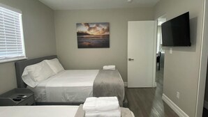 A hotel room with two beds, a flat-screen TV, a painting, and a wooden floor. - Looking in Orlando / Kissimmee great Location 2/1  (Kissimmee)