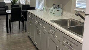 A modern kitchen with grey cabinets, a double sink, and a dining area with a table and chairs. - Looking in Orlando / Kissimmee great Location 2/1  (Kissimmee)
