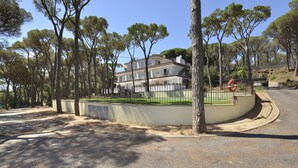 Zona residencial con una casa de dos pisos, un jardín cercado y una calle con una señal de tráfico.