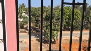 A view through metal bars, featuring a road, greenery, and a distant building. - 2-Bed Penthouse in Mtwapa with Rooftop Terrace (Mtwapa)