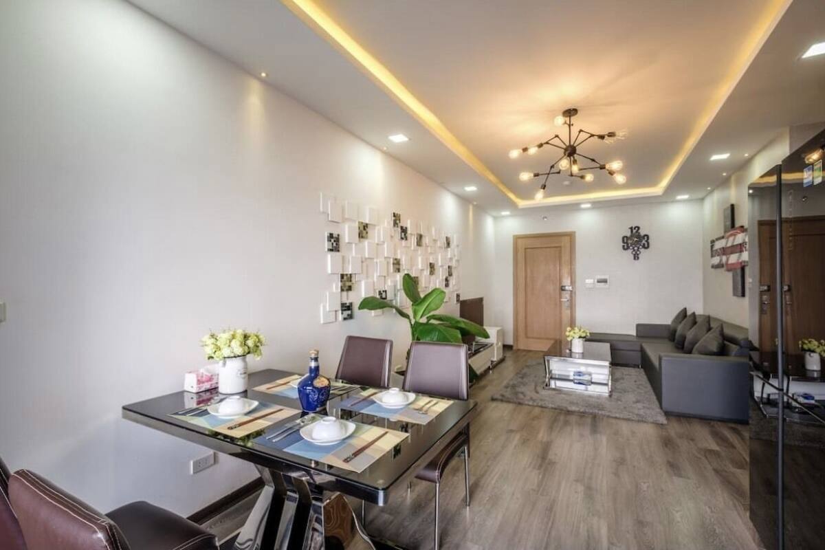 A modern living room with a dining area, featuring a sofa, a coffee table, and a dining table set for four.