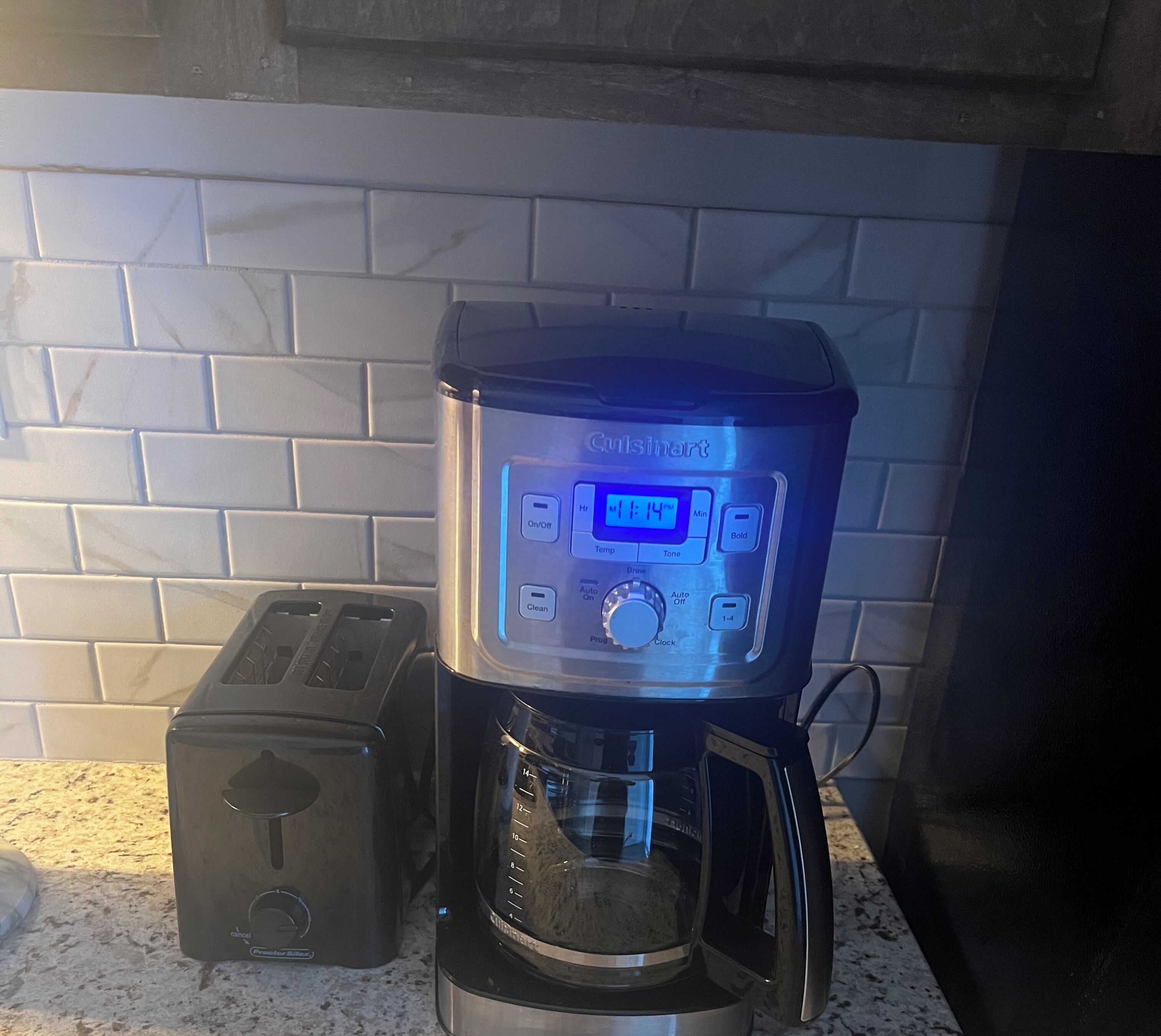 Una cafetera Cuisinart con pantalla digital, un tostador y una jarra de café sobre una encimera de cocina.