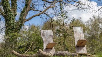 Two wooden sculptures in a natural setting with trees and a clear sky.