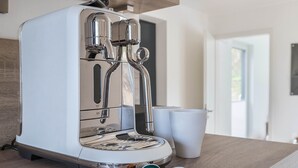 Una cocina moderna con una máquina de espresso integrada, una encimera de madera y dos tazas blancas.
