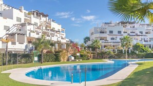 Une piscine à bord incurvé, entourée d’une pelouse bien entretenue et de palmiers.