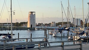 A marina with boats docked, a lighthouse, and a wooden pier. - Apartment 'Koje 1' with Private Terrace and Private Garden (Fehmarn)