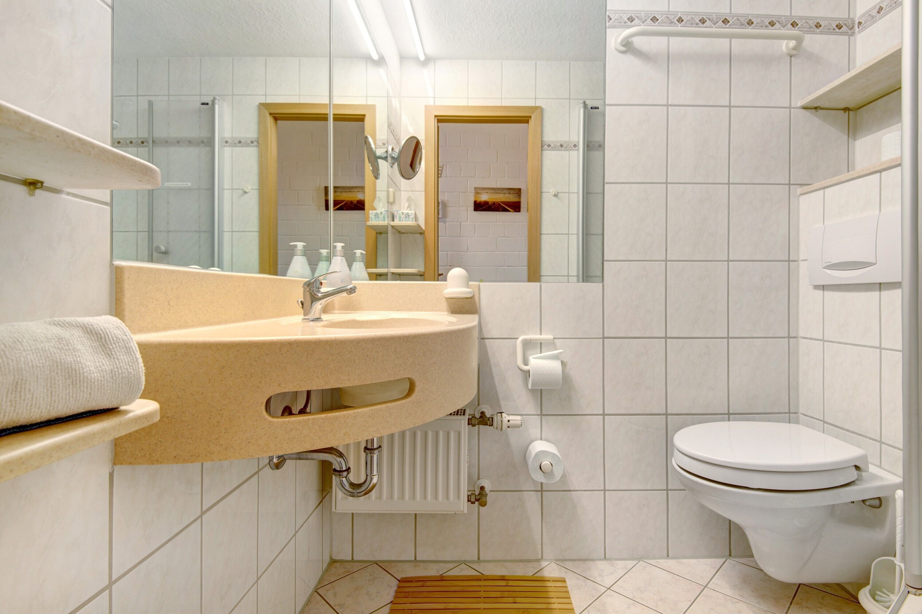 Een badkamer met een wastafel, spiegel, toilet en douche.