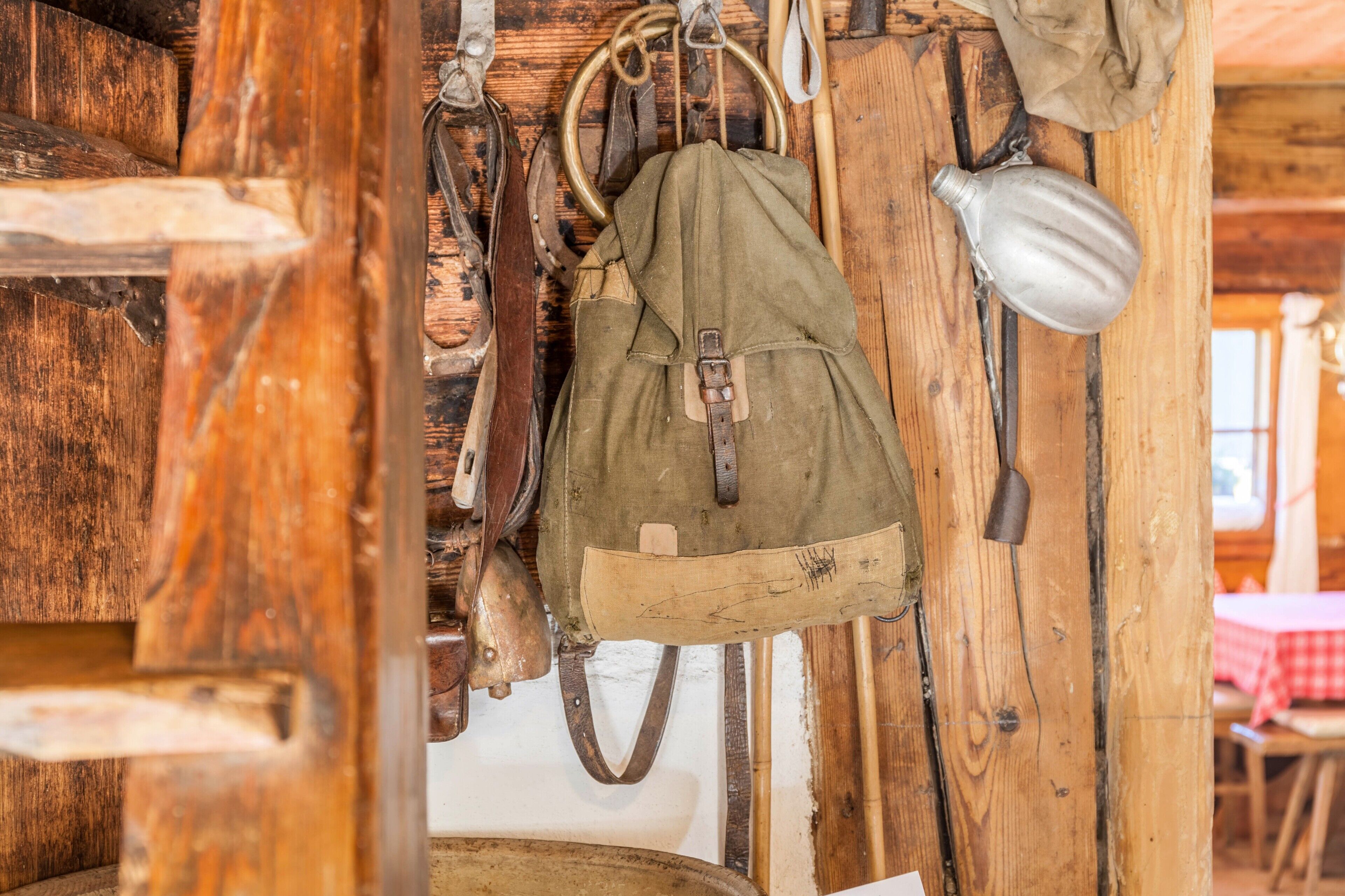 Ein rustikales Holzinnere mit einer hängenden Tasche, einem Metallbehälter und einer Holztür.