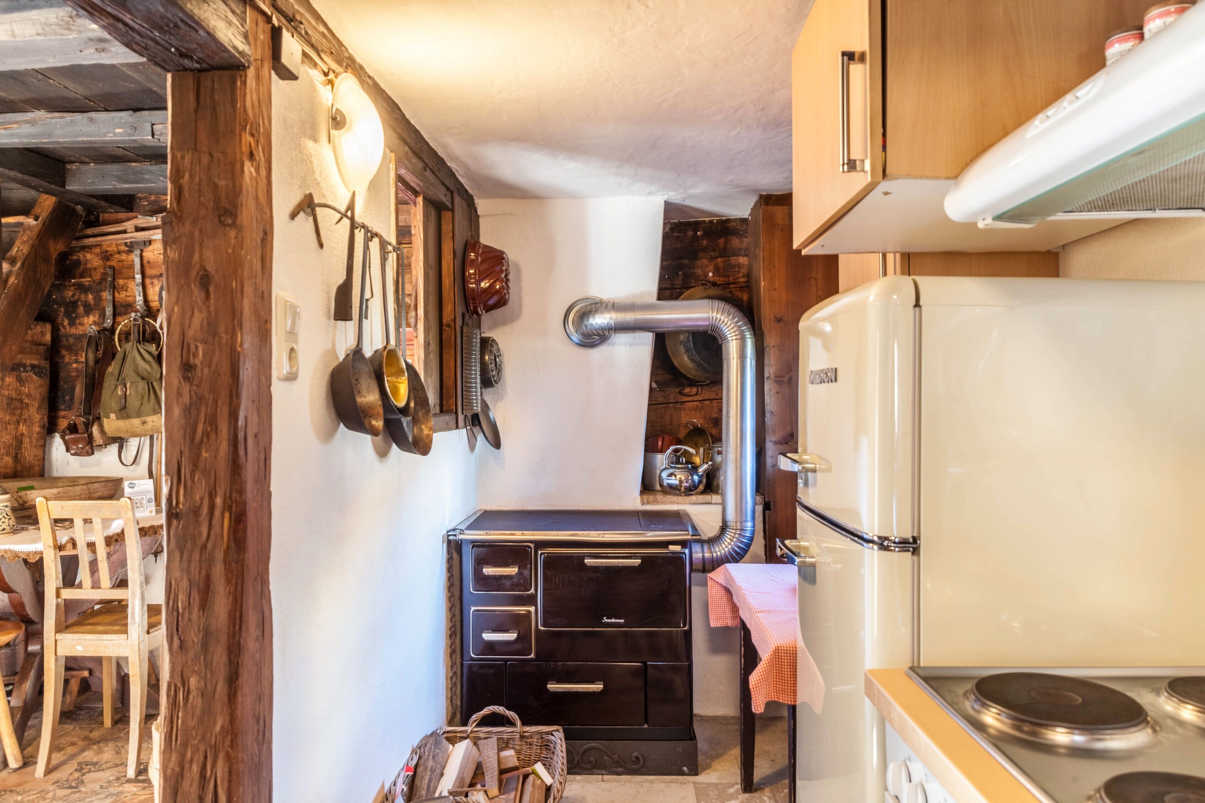 A compact kitchen with a stove, a refrigerator, and wooden cabinets.