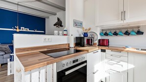 A modern kitchen with a wooden countertop, built-in oven, and white cabinetry. - Vacation Home "Deich Hus" with Private Terrace, Garden & Wi-Fi (Büsumer Deichhausen)