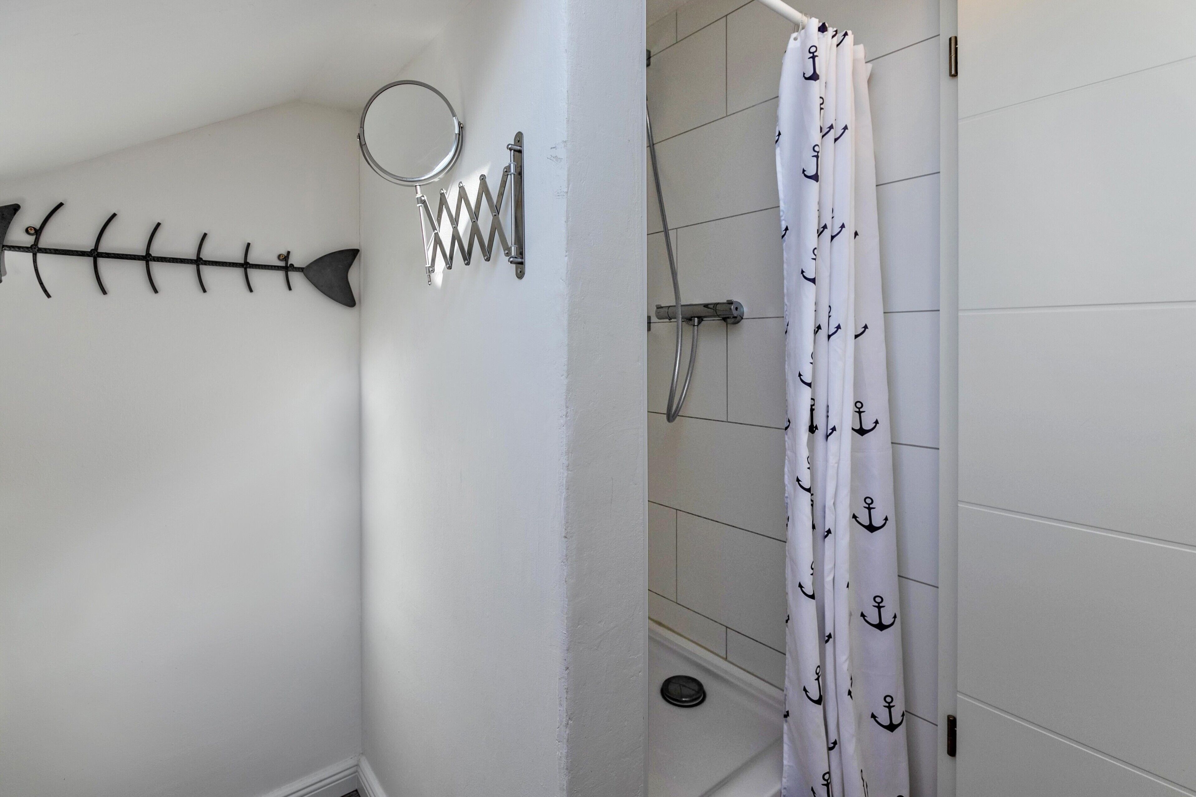 Ein Badezimmer mit Duschvorhang, Handtuchhalter und einer Wanddekoration in Form eines Metalfisches.