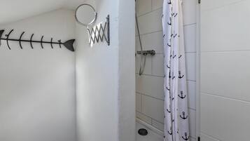 Ein Badezimmer mit Duschvorhang, Handtuchhalter und einer Wanddekoration in Form eines Metalfisches.