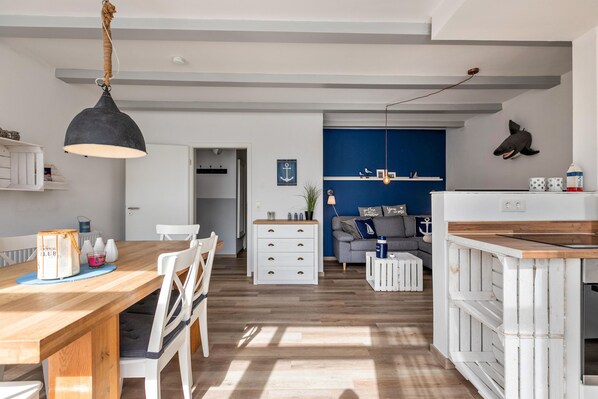 Uma cozinha moderna com ilha de madeira, armários brancos e luminária pendente.