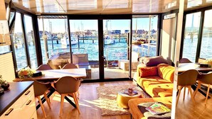 A modern interior with a large window offering a marina view, a dining area, and a cozy seating space.