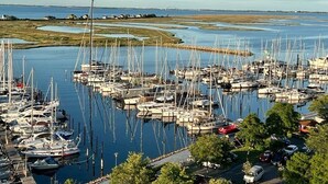 A marina with numerous boats docked, surrounded by water and land.