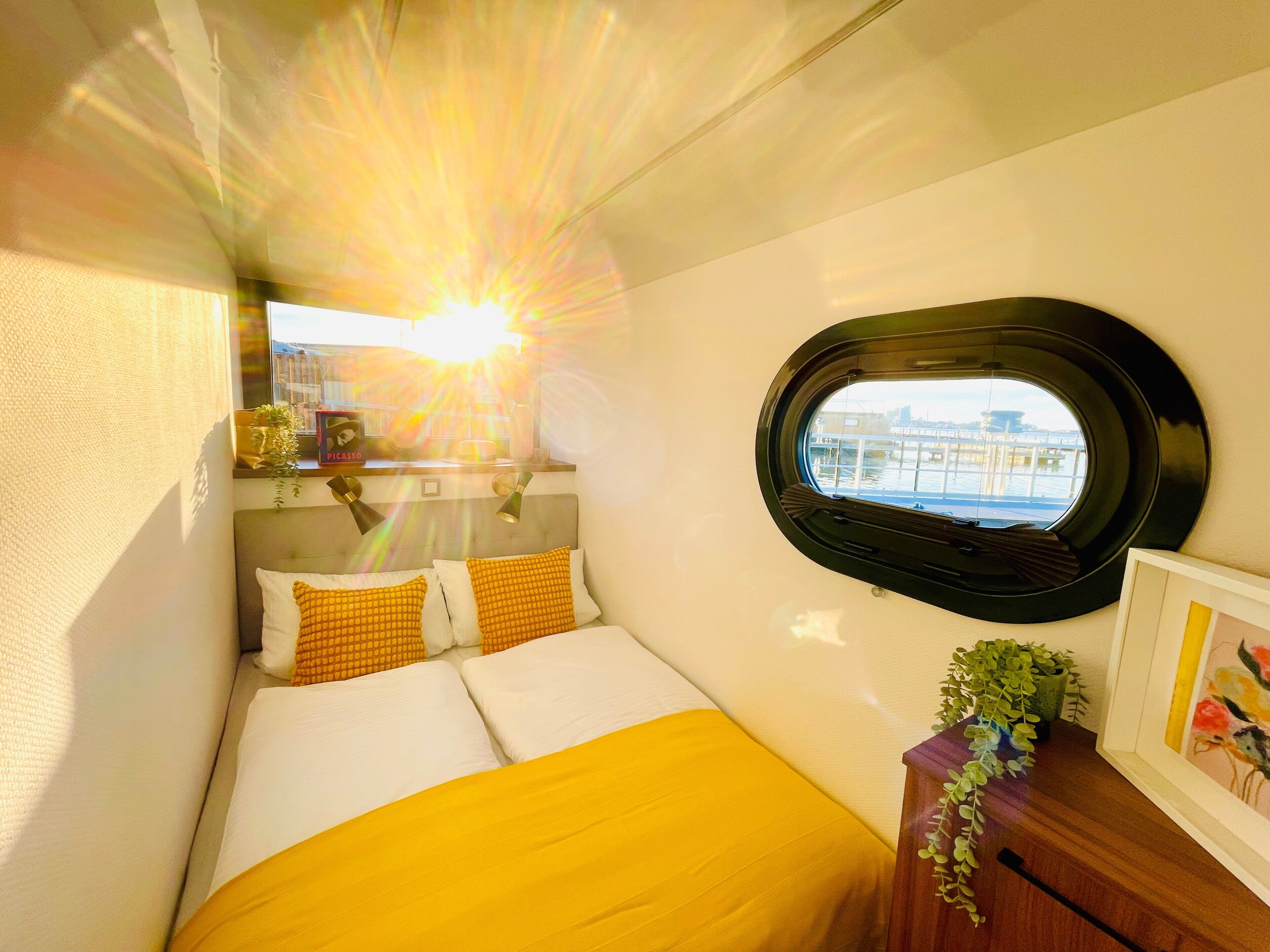 Una camera da letto compatta con un letto, una finestra, un comodino e vista sulla città.