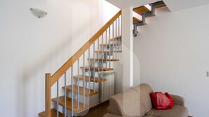 Eine Treppe mit Holzstufen und Metallgeländern, die zu einem Zwischenpodest mit einem Heizkörper führt.