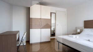 Une chambre d’hôtel moderne équipée d’un lit, d’un bureau, d’une chaise et d’une armoire.