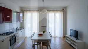 Una cocina moderna con una mesa de comedor, sillas, un televisor y una estufa.