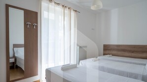A hotel room with two beds, a wooden headboard, a large mirror, and a window with sheer curtains. - Kurioso - Three-room apartment ground floor with garden (Pineto)