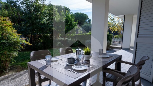 An outdoor patio with a table set for two, surrounded by chairs, and a potted plant on the table. - Kurioso - Three-room apartment ground floor with garden (Pineto)