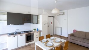 Una cocina moderna con armarios blancos, una mesa de comedor con platos y vasos, y un sofá en la sala de estar.