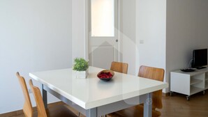 A dining area with a white table, two wooden chairs, a small potted plant, and a bowl of red berries. - Karismatico - Three-room apartment on the first floor a few steps from the sea (Pineto)